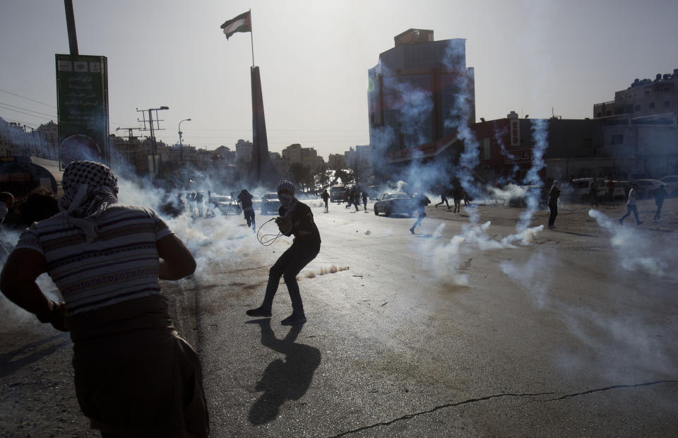 Palestinian demonstrators run from tear gas fired by Israeli troops during the protest against the U.S. announcement that it no longer believes Israeli settlements violate international law., at checkpoint Beit El near the West Bank city of Ramallah, Tuesday, Nov. 26, 2019, (AP Photo/Majdi Mohammed)