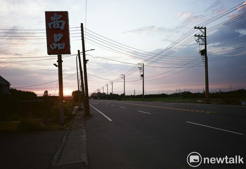 筆直寬闊的四線車道、半空中的廣告看板、電線和電線桿佈滿夕陽餘暉的天際線，空曠的桃園沿海地景中，有著許多不可言說的隱喻。   圖：余白攝影/提供