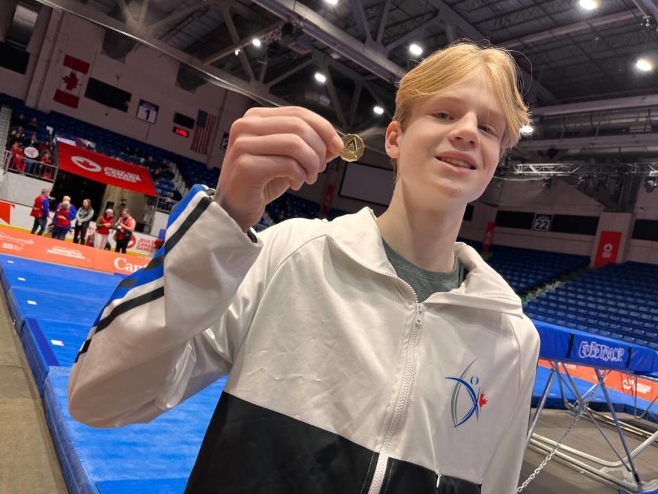 Cody Cyman, a trampolinist from Alberta, holds one of the specially-made lucky loonies his team brought to the Canada Games to spread good luck among competitors.  (Jessica Doria-Brown/CBC - image credit)