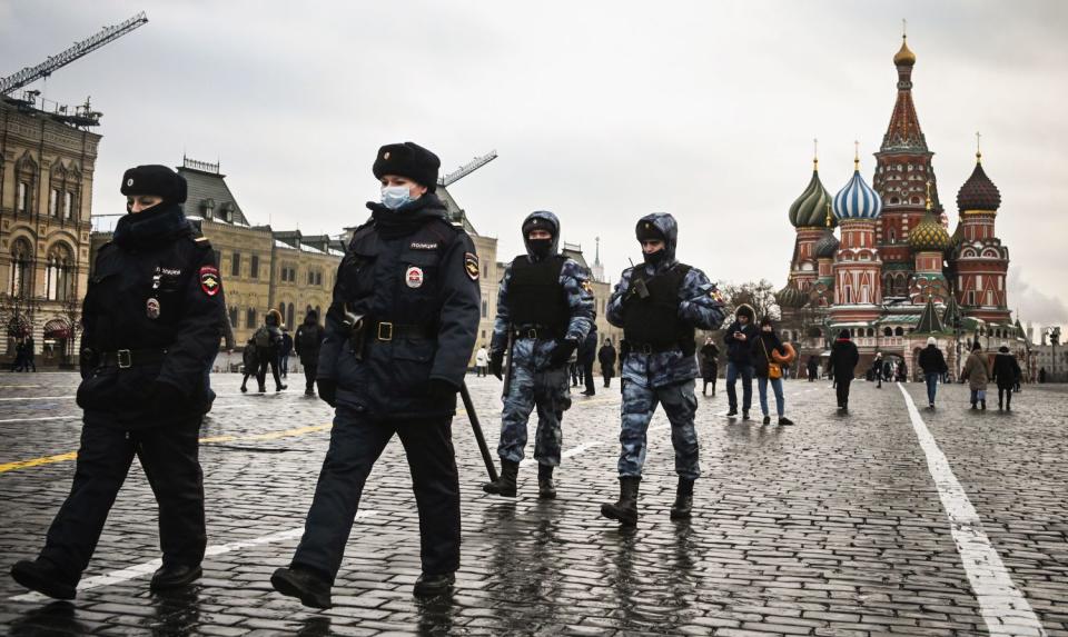 St. Basil's Cathedral is in the background as four officers walk through a lightly populated Red Square.