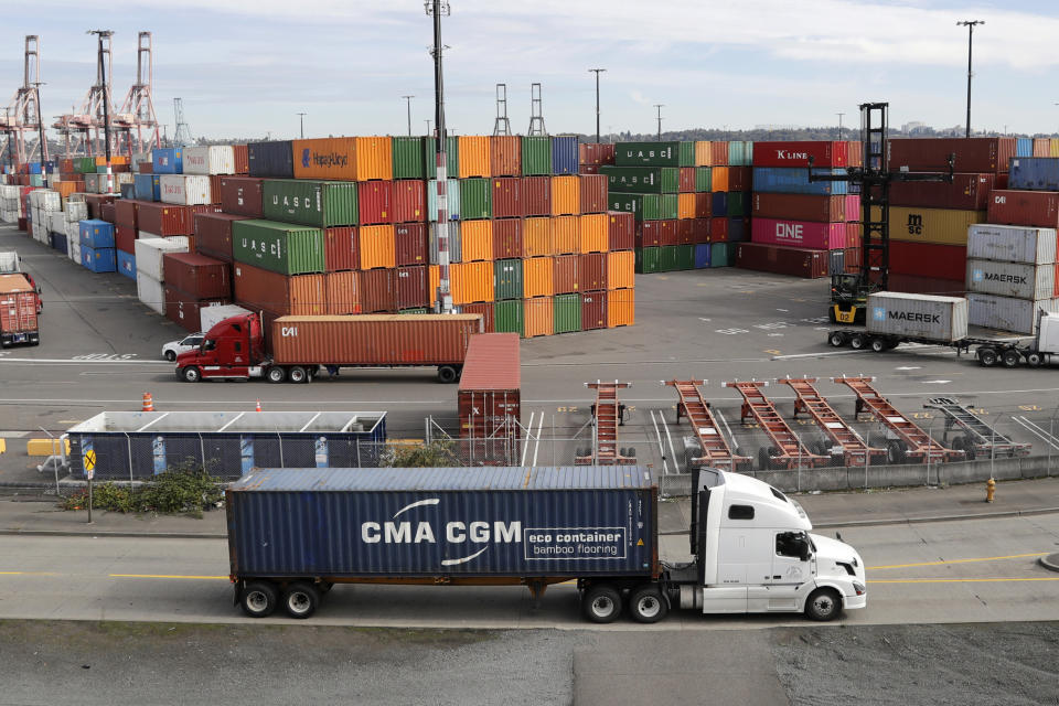 FILE - In this Oct. 2, 2019, file photo trucks hauling shipping containers drive near containers stacked five-high at a terminal on Harbor Island in Seattle. Defying fears and predictions, the American job market is still shrugging off President Donald Trump’s trade wars. Employers added an impressive 266,000 jobs in November, and unemployment returned to a 50-year low 3.5% _ all at a time when the Trump administration is engaged in a bruising trade war with China while fighting other U.S. trading partners as well.(AP Photo/Elaine Thompson, File)