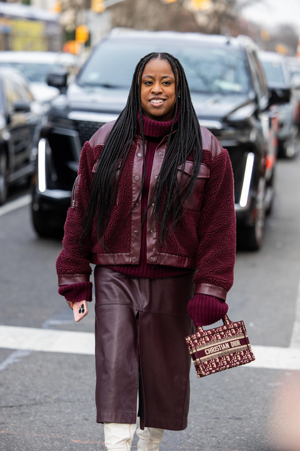 A woman at fashion week in a burgundy jacket and leather shorts