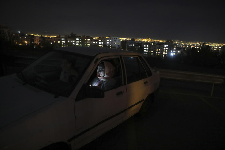 People sit in their cars watching a movie at a new drive-in cinema on a car parking area of the Milad telecommunications tower, as regular theaters are closed due to the coronavirus outbreak, Friday, May 1, 2020. Iran is the region's epicenter of the COVID-19 pandemic. (AP Photo/Vahid Salemi)