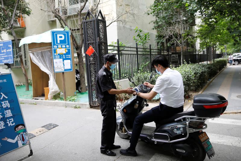 Security guard takes body temperature measurement of a man in Beijing