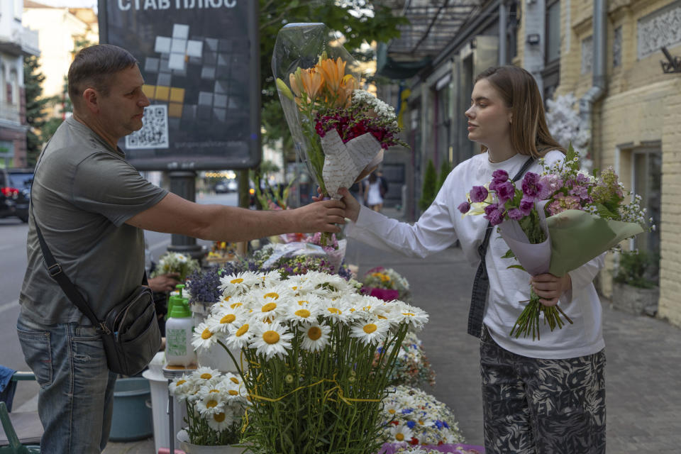 A woman buys bouquets of flowers at a street flower stall in Kyiv, Ukraine, Tuesday, June 25, 2024. Despite hardships brought by war flowers fill Kyiv and other Ukrainian cities. They burst out of planters that line the capital's backroads and grand boulevards and are fixed to lampposts. (AP Photo/Anton Shtuka)