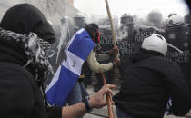 Protestors clash with riot police on the sidelines of a rally in Athens, Sunday, Jan. 20, 2019. Greece's Parliament is to vote this coming week on whether to ratify the agreement that will rename its northern neighbor North Macedonia. Macedonia has already ratified the deal, which, polls show, is opposed by a majority of Greeks. (AP Photo/Yorgos Karahalis)