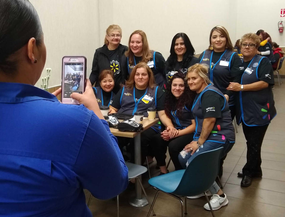 Walmart employees in El Paso, Texas, pose for a photo taken by a McDonald's employee in the restaurant inside the Walmart that reopened Thursday, Nov. 14, 2019, after a mass shooting that killed in 22 people in August. Since then Walmart has quietly hired off-duty officers at all of its stores in the El Paso area. (AP Photo/Cedar Attanasio)