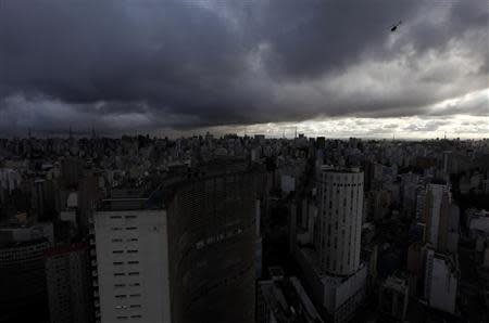 An helicopter (R) flies over the sky of the city of Sao Paulo April 24, 2014. REUTERS/Paulo Whitaker