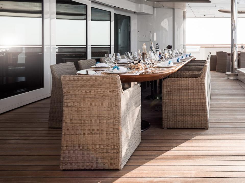 The pool on an outdoor deck next to a long dining table.