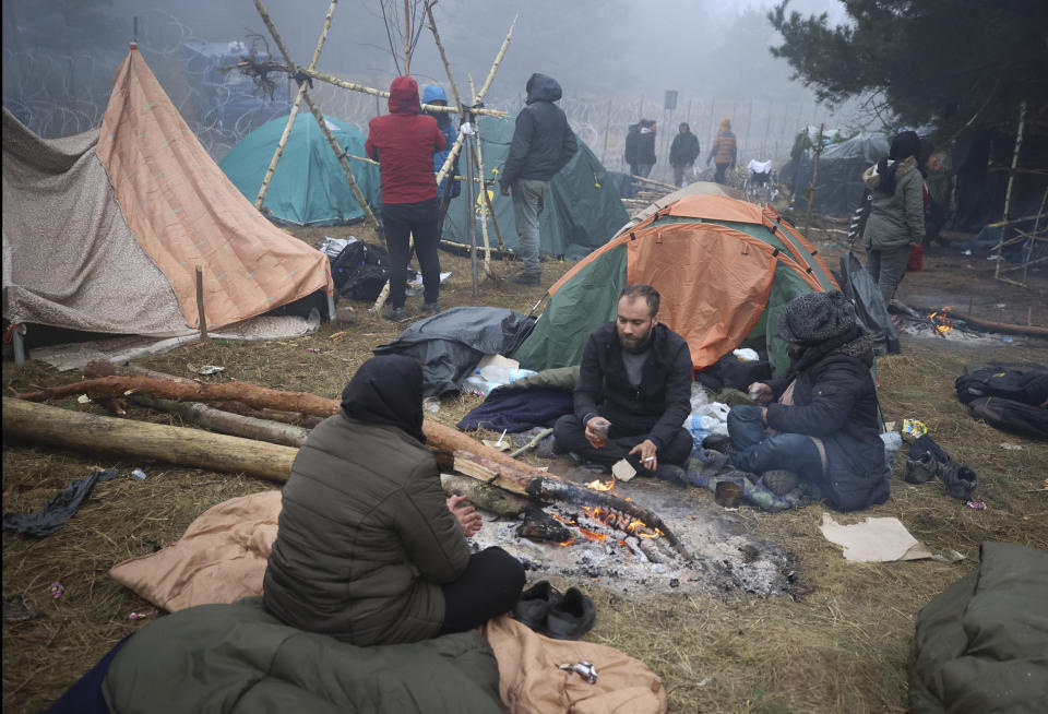 FILE - Migrants from the Middle East and elsewhere warm up at the fire gathering at the Belarus-Poland border near Grodno, Belarus, Thursday, Nov. 11, 2021. The European Union has accused Belarus' authoritarian President Alexander Lukashenko of encouraging illegal border crossings as a "hybrid attack" to retaliate against EU sanctions on his government for its crackdown on internal dissent after Lukashenko's disputed 2020 reelection. (Leonid Shcheglov/BelTA via AP, File)