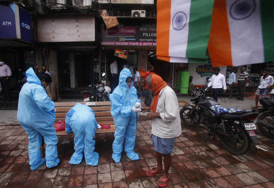 Community health workers screen a man for COVID-19 symptoms in Dharavi, one of Asia's biggest slums, in Mumbai, India, Saturday, Aug. 15, 2020. India's coronavirus death toll overtook Britain's to become the fourth-highest in the world with another single-day record increase in cases Friday. (AP Photo/Rafiq Maqbool)