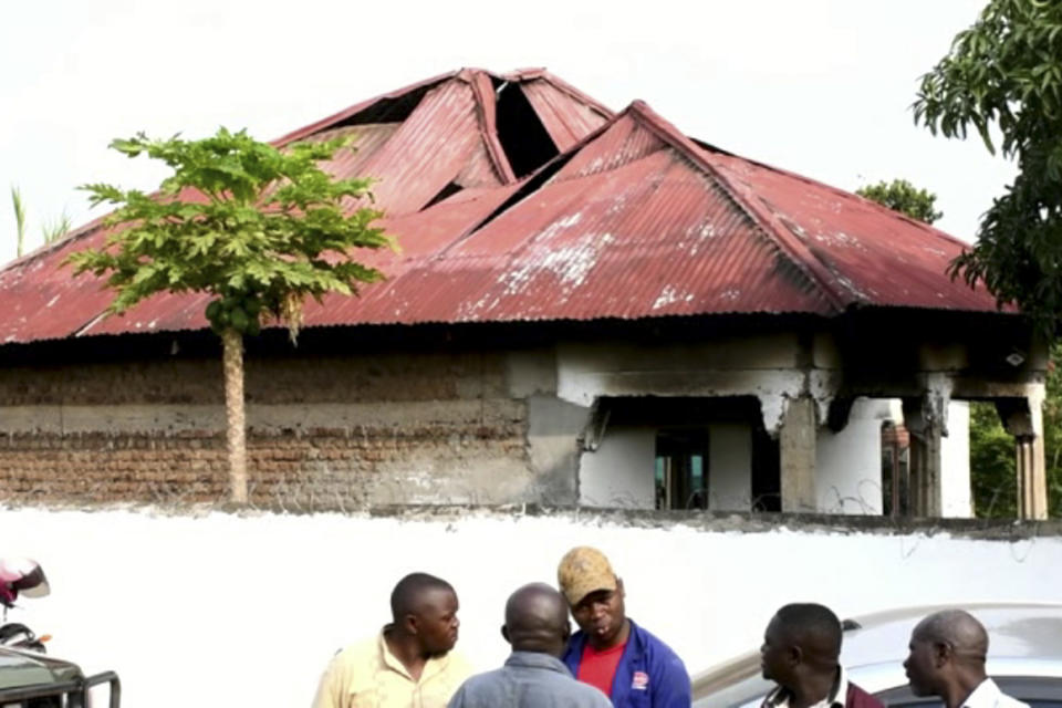In this image made from video, people gather in front of a building of the Lhubiriha Secondary School following an attack on the school near the border with Congo, in Mpondwe, Uganda, Saturday, June 17, 2023. Ugandan authorities recovered the bodies of dozens of people including students who were burned, shot or hacked to death after suspected rebels attacked the school, the local mayor said Saturday. (AP Photo)
