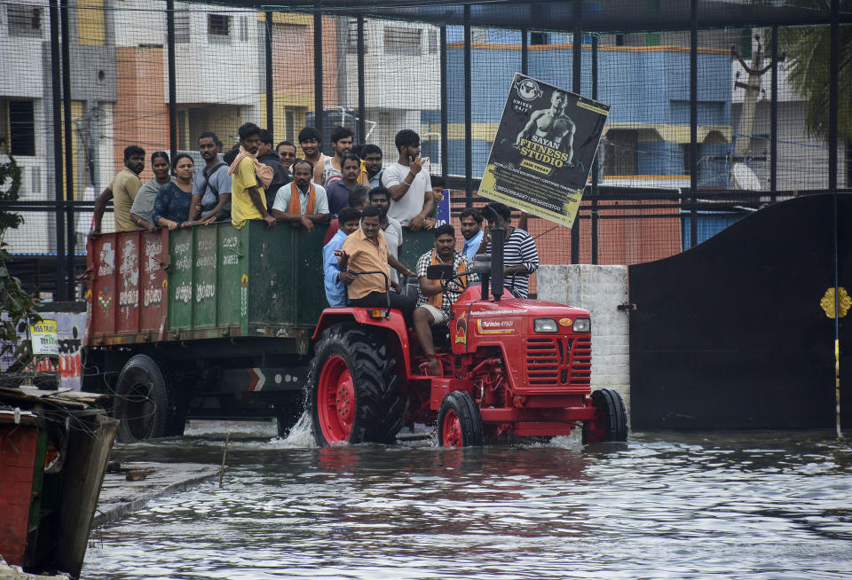 People are evacuated from flooded areas on a tractor following heavy rains along the Bay of Bengal coast in Chennai, India, Tuesday, Dec.5, 2023. Tropical Storm Michaung began making landfall along India's southeastern coastline Tuesday, bringing with it torrential rains and strong winds. (AP Photo)