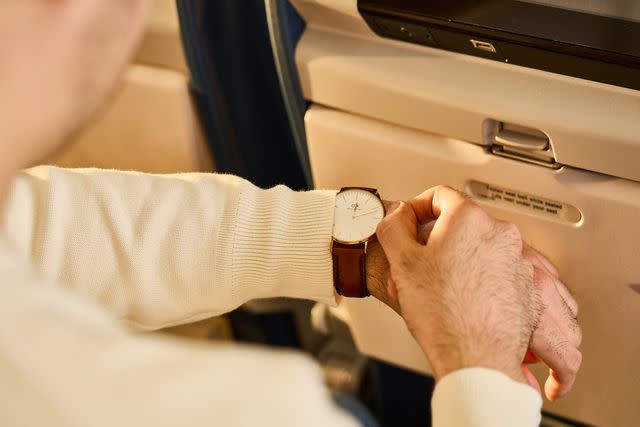 <p>Margot Cavin/Travel + Leisure</p> Plane passenger adjusting his watch.