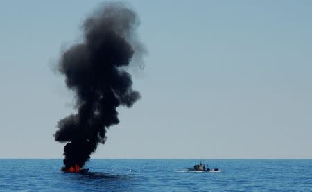 A migrant boat is set on fire by the Libyan coastguard after NGO ships rescued the migrants about 20 miles off the coast of Western Libya, May 18, 2017. Picture taken May 18, 2017. REUTERS/Steve Scherer