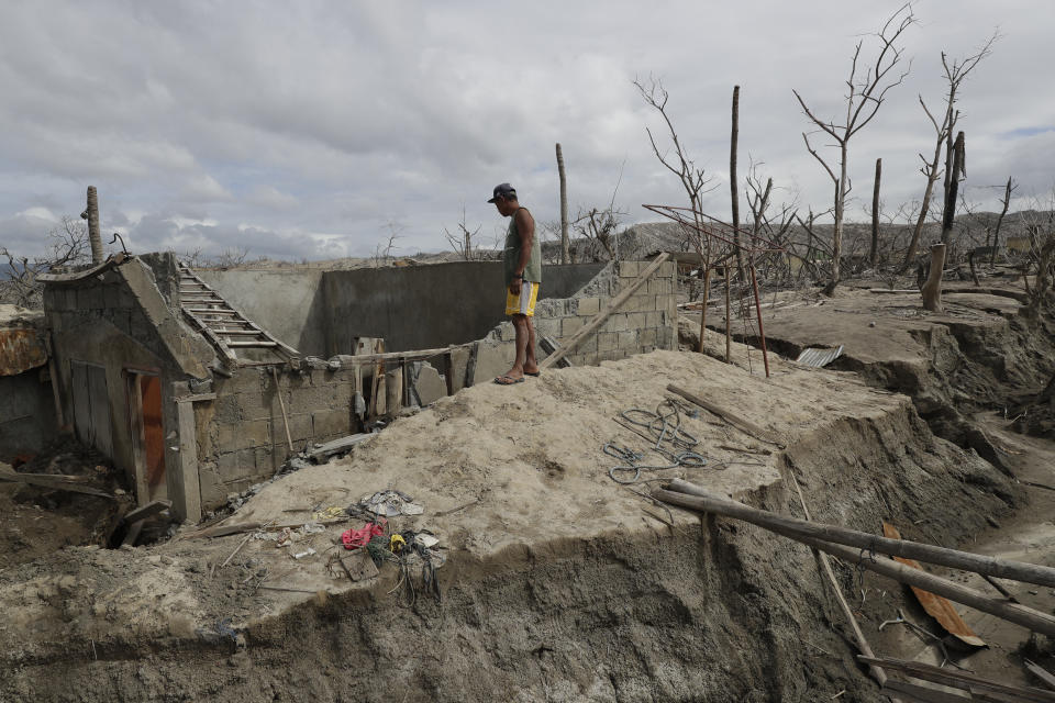 Fisherman Rogelito Cacao looks at the remains of his house at the Taal volcano almost a year after it erupted on Sunday, Jan. 10, 2021 in Batangas province, Philippines. Cacao regularly visits the area after feeding fish at the pens on the Taal lake. A popular tourist destination just south of Manila because of its picturesque setting in the middle of a lake, Taal erupted on Jan. 12, 2020. The eruption displaced thousands of villagers living near the area and delivered an early crisis this year for one of the world's most disaster-prone nations a couple of months before the COVID-19 pandemic broke in the country. (AP Photo/Aaron Favila)