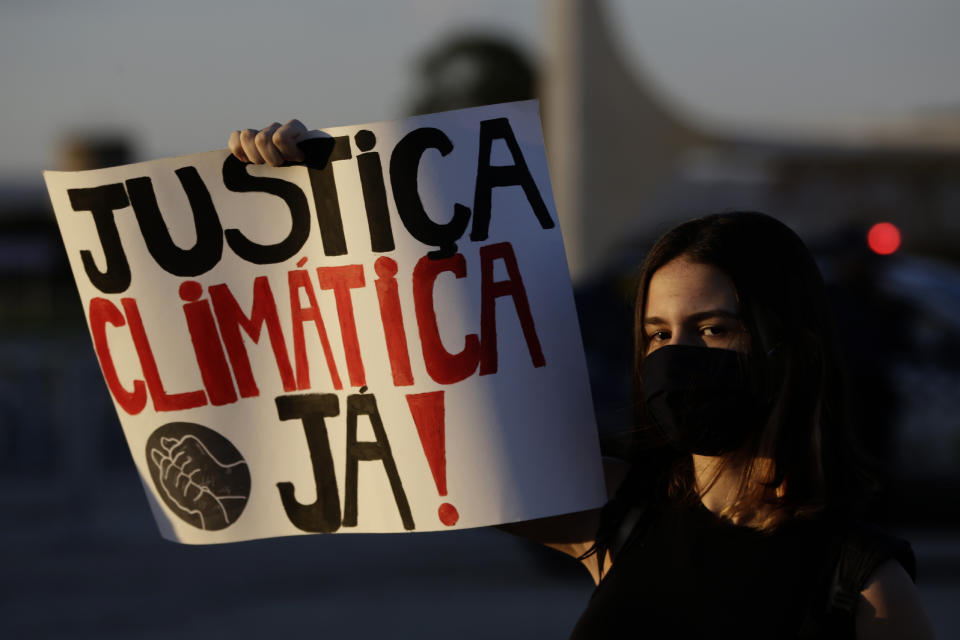 A woman holds a sign reading "Climate Justice Now!" during a protest against Bolsonaro's environmental policies in the Brazilian capital of Brasilia. Bolsonaro has faced domestic and international pressure to alter his approach to the environment. (Photo: AP Photo/Eraldo Peres)