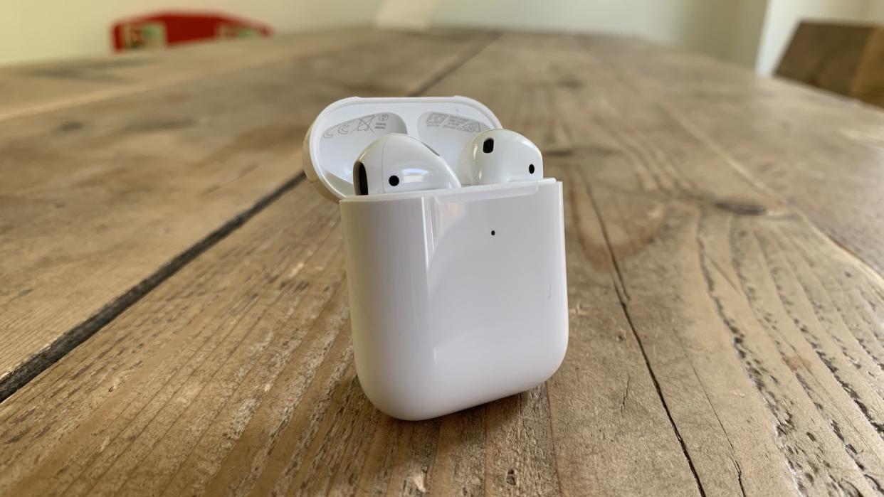  Apple AirPods (2019) in their charging case on a wooden table. 