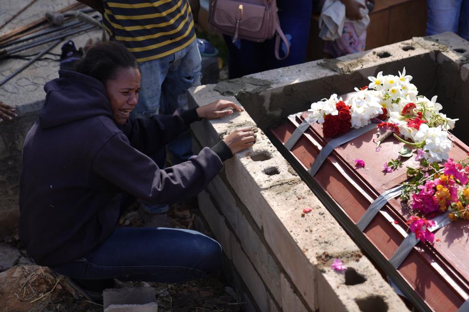 A sister of miner Santiago Mora cries as he is buried at the cemetery in La Paragua, Bolivar state, Venezuela, Thursday, Feb. 22, 2024. The collapse of an illegally operated open-pit gold mine in central Venezuela killed at least 14 people and injured several more, state authorities said Wednesday, as some other officials reported an undetermined number of people could be trapped. (AP Photo/Ariana Cubillos)