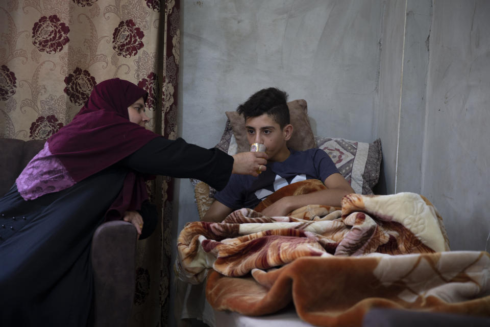 Palestinian youth, Tareq Zubeidi, 15, rests at his house, in the West Bank village of Silat ad-Dhahr, Tuesday, Aug. 31, 2021. Zubeidi says he was abducted and beaten by a group of Israeli settlers after they found him and his friends eating snacks near an evacuated hilltop settlement in the occupied West Bank. More than two weeks after the Aug. 17 incident, he says he can barely walk and is afraid to leave his home. (AP Photo/Majdi Mohammed)