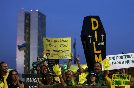 A man holds a mock coffin at a protest against Brazil's President Dilma Rousseff calling for her impeachment in front of the Brazilian National congress in Brasilia, Brazil, May 11, 2016. The poster (C) reads, "With Lula and Dilma, Brazil became a misfortune". REUTERS/Paulo Whitaker