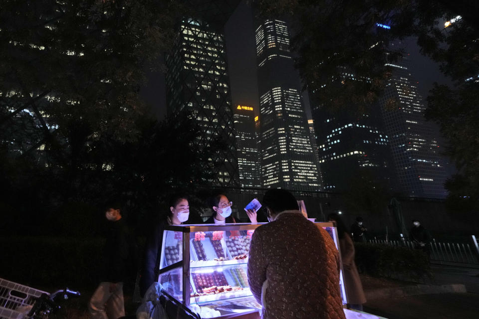 Residents wearing masks buy candied haw from a street vendor in Beijing, Thursday, Nov. 10, 2022. (AP Photo/Ng Han Guan)