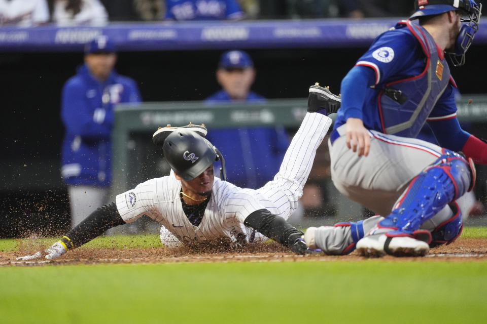 Colorado Rockies' Ezequiel Tovar, left, scores on single by Elias Díaz as Texas Rangers catcher Jonah Heim, right, fields the throw in the fifth inning of a baseball game Friday, May 10, 2024, in Denver. (AP Photo/David Zalubowski)