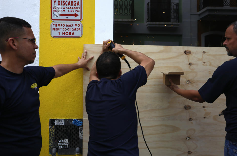 Unos hombres cubrían la entrada de un local con tablas de madera, en San Juan, Puerto Rico, antes de que pasara por la isla del huracán María. EFE/Thais Llorca