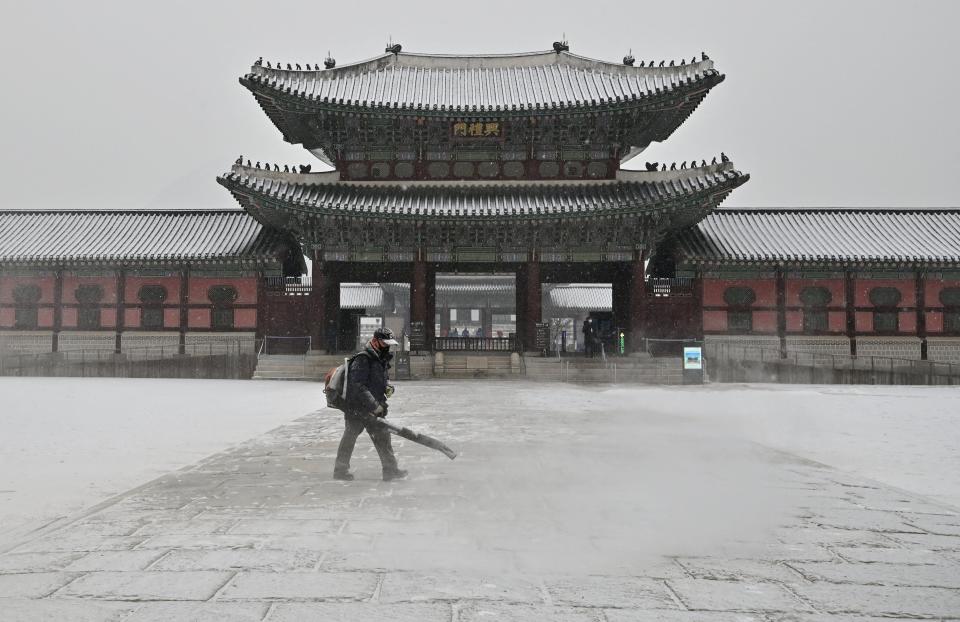 A worker uses a blower to clear snow at Gyeongbokgung Palace in central Seoul on January 19, 2022.