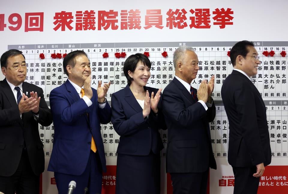 Japan's Prime Minister and ruling Liberal Democratic Party leader Fumio Kishida, right, poses with key party members at the party headquarters in Tokyo, Sunday, Oct. 31, 2021. Japanese Prime Minister Fumio Kishida’s governing coalition is expected to keep a majority in a parliamentary election Sunday but will lose some seats in a setback for his weeks-old government grappling with a coronavirus-battered economy and regional security challenges, according to exit polls. (Behrouz Mehri, Pool via AP)