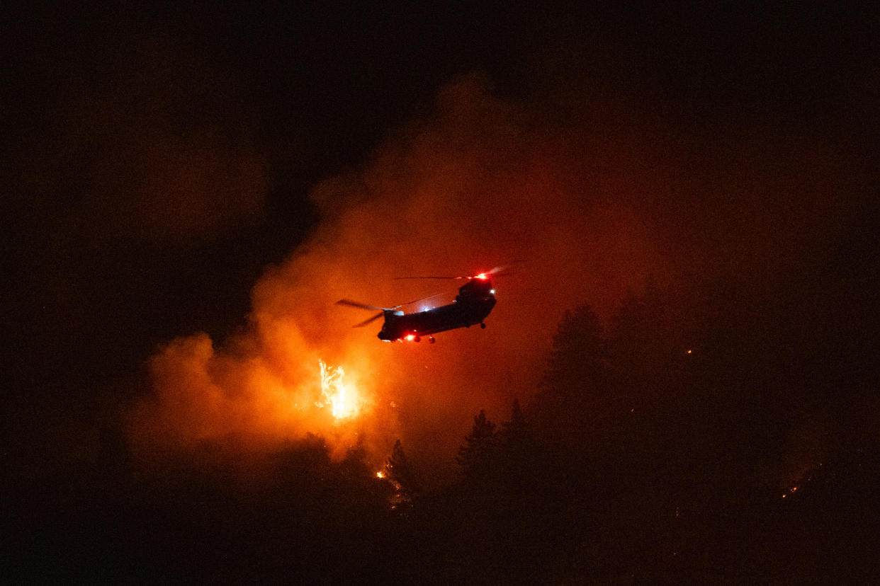 A water-dropping helicopter over flames.