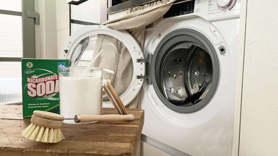 baking soda on wooden bench in front of open washing machine