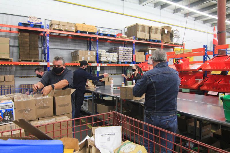 Volunteers tape boxes and sort through donated food at the Ottawa Food Bank warehouse in Ottawa