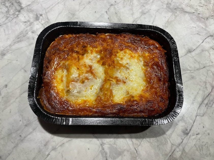 A black container of Trader Joe's baked family-style lasagna on a gray counter