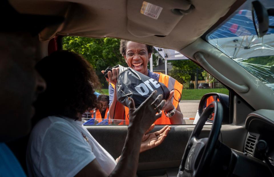 Shannon Johnson, a DTE Energy employee, smiles as she gives a care package to a Detroit resident during a storm relief giveaway Saturday at a Meijer parking lot in Detroit.