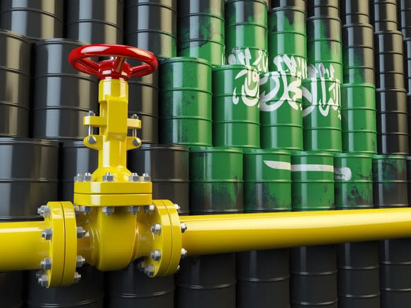 Oil-pipeline valve in front of barrels painted like the Saudi flag