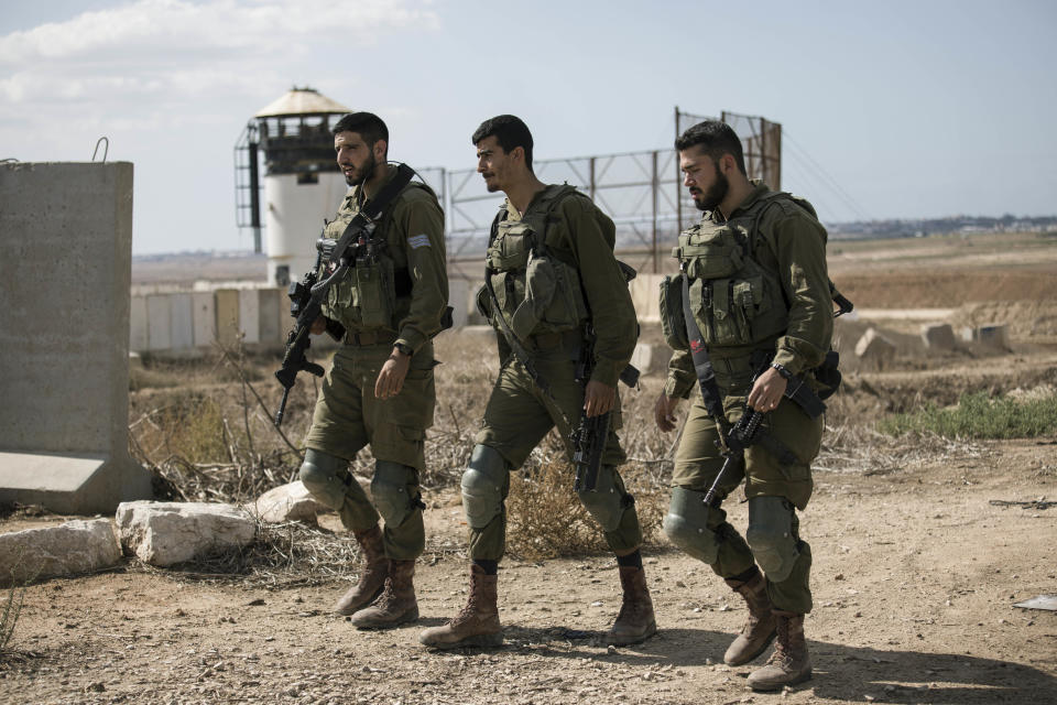 Israeli soldiers walk by an outpost near the Gaza Strip border, Saturday, Oct. 27, 2018. The Israeli military has struck dozens of targets across the Gaza Strip in response to heavy rocket fire and threatened to expand its air campaign to Syria after accusing Iranian forces in Damascus of orchestrating the rocket attacks. (AP Photo/Tsafrir Abayov)