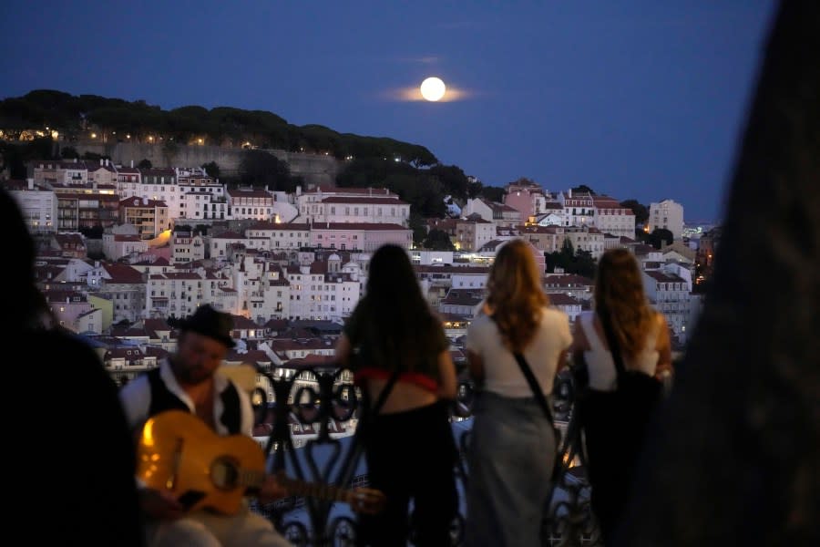 People watch a supermoon rise above Lisbon, Wednesday, Aug. 30, 2023. It’s the month’s second supermoon, when a full moon appears a little bigger and brighter thanks to its slightly closer position to Earth. (AP Photo/Armando Franca)