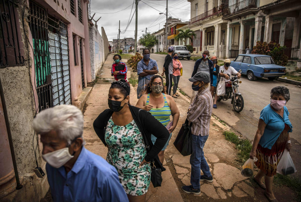 Yuliet Colon, center in tank top, waits her turn outside an agricultural market in Havana, Cuba, Friday, April 2, 2021. Colon is among several Cubans who, with more ingenuity than resources, help their compatriots cope with shortages exacerbated by the new coronavirus pandemic with Facebook posts of culinary creations designed around what they're actually likely to find at the market or with government rations. (AP Photo/Ramon Espinosa)