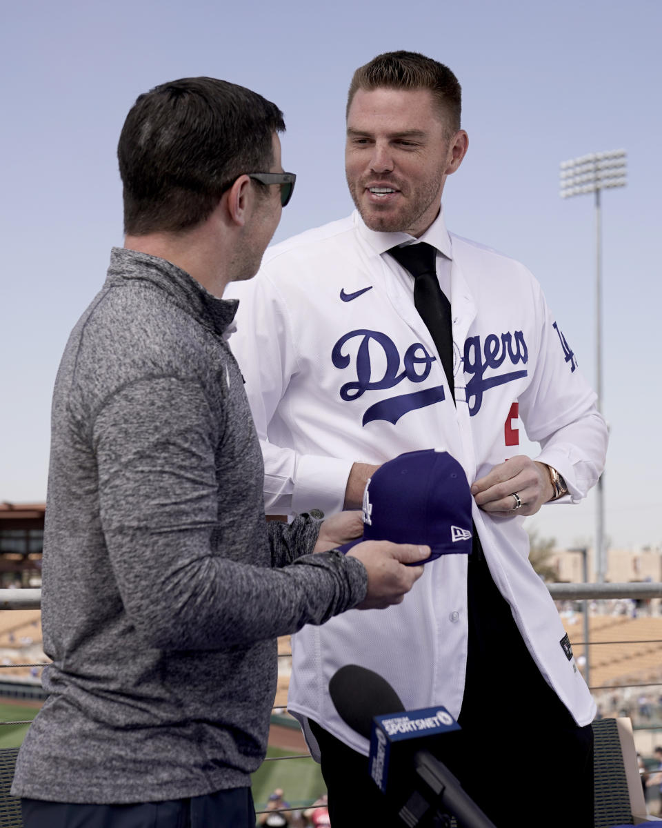 Los Angeles Dodgers president of baseball operations Andrew Friedman, left, announces the arrival of free agent Freddie Freeman during a news conference at spring training baseball, Friday, March 18, 2022, in Glendale, Ariz. (AP Photo/Charlie Riedel)