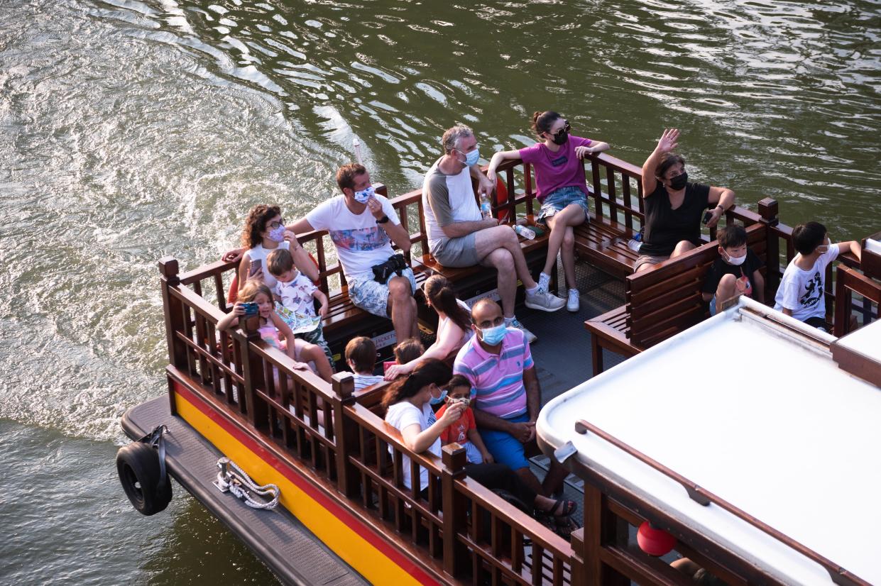 People wearing masks ride a tourist boat along the Singapore River. (PHOTO: Getty Images)