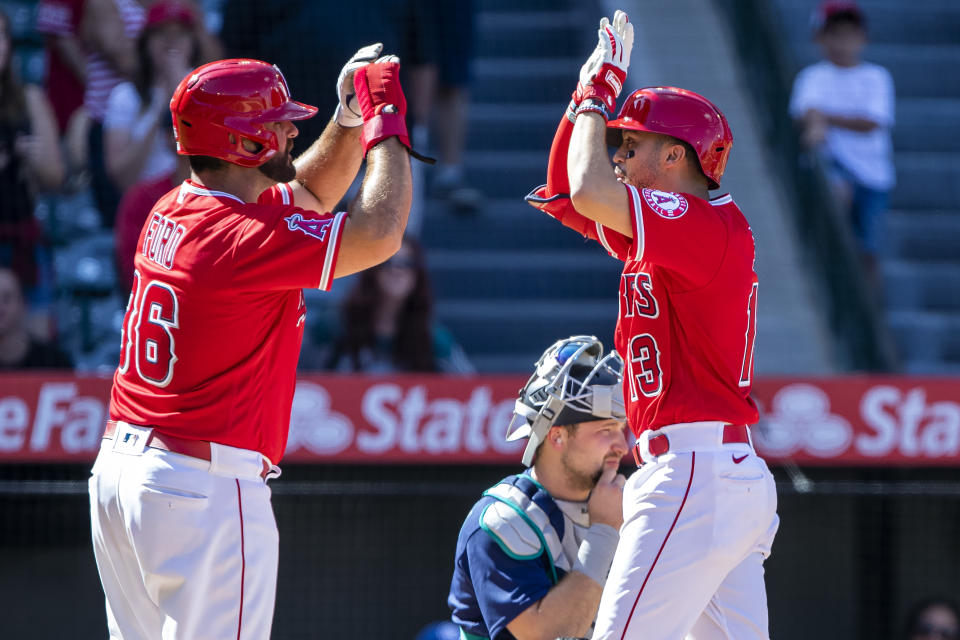 Los Angeles Angels' Mike Ford, left, congratulates Livan Soto for hitting a two-run home run as Seattle Mariners catcher Cal Raleigh, center below, looks away, during the seventh inning of a baseball game in Anaheim, Calif., Sunday, Sept. 18, 2022. (AP Photo/Alex Gallardo)