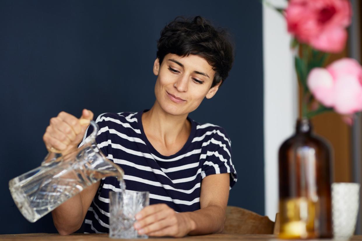 person pouring water from pitcher into glass