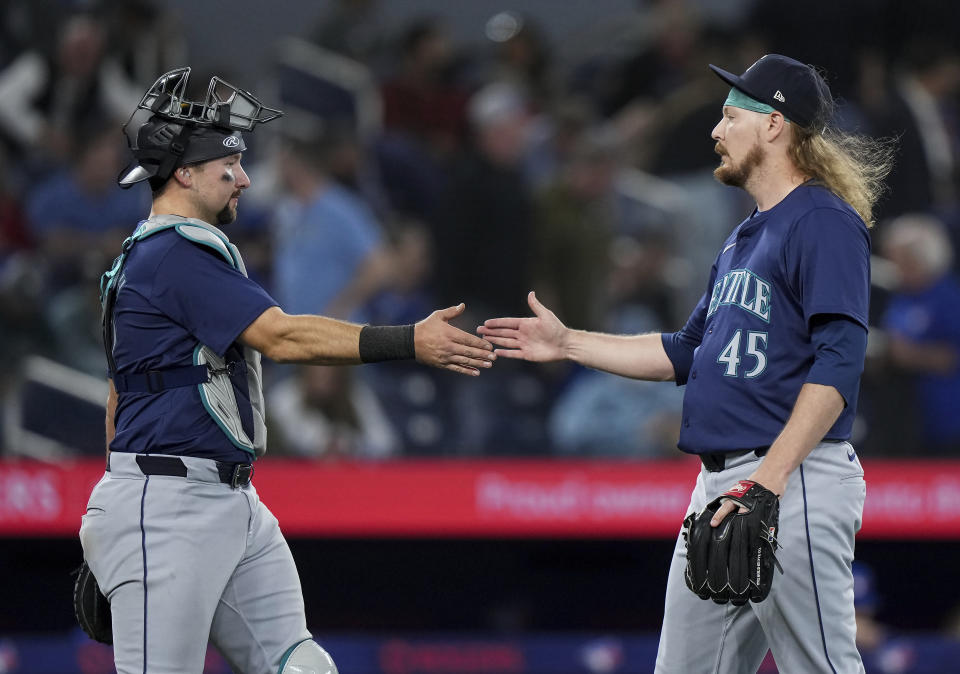 Seattle Mariners catcher Cal Raleigh, left, celebrates with Ryne Stanek (45) after the team's win over the Toronto Blue Jays in 10 innings in a baseball game Wednesday, April 10, 2024, in Toronto. (Nathan Denette/The Canadian Press via AP)