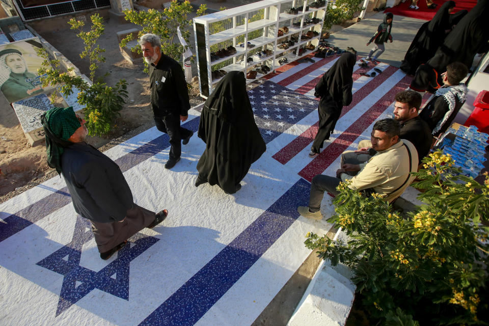 People walk walk over Israeli and American flags during a third anniversary assassination of Abu Mahdi al-Muhandis, deputy commander of Iran-backed militias in Iraq known as the Popular Mobilization Forces and Iran's top general Qassam Soleimani at cemetery in Najaf, Iraq, Monday, Jan. 2, 2023. Al-Muhandis and Soleimani were killed in an US air strike in Baghdad in 2020. , (AP Photo/Anmar Khalil)