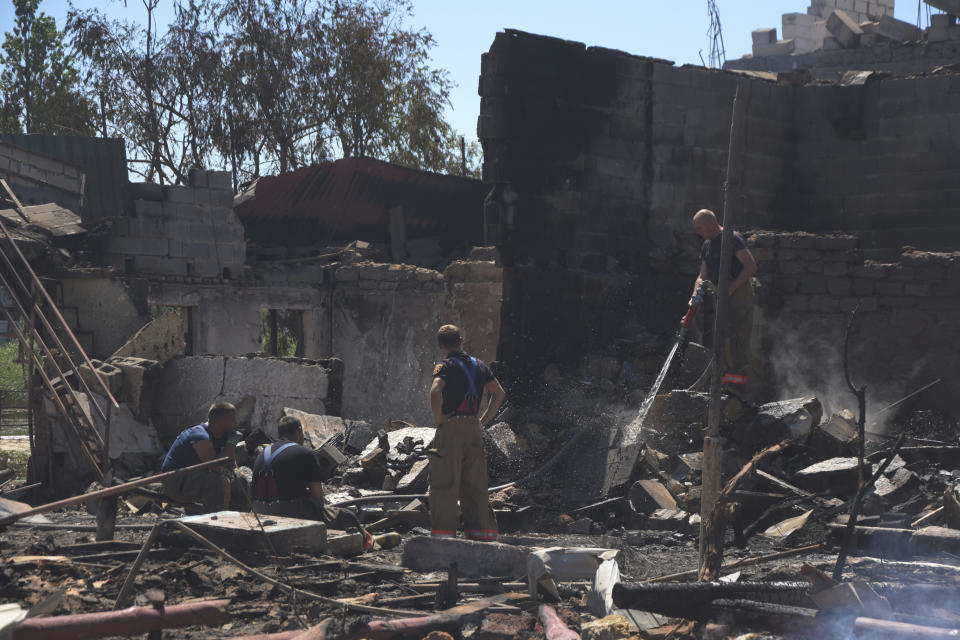 Firefighters work at a damaged residential building following Russian shelling on the outskirts of Odesa, Ukraine, Tuesday, July 26, 2022. (AP Photo/Michael Shtekel)