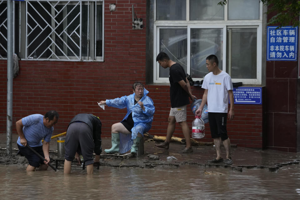 Residents work in the aftermath of flood waters from an overflowing river in the Mentougou district on the outskirts of Beijing, Tuesday, Aug. 1, 2023. Chinese state media report some have died and others are missing amid flooding in the mountains surrounding the capital Beijing. (AP Photo/Ng Han Guan)
