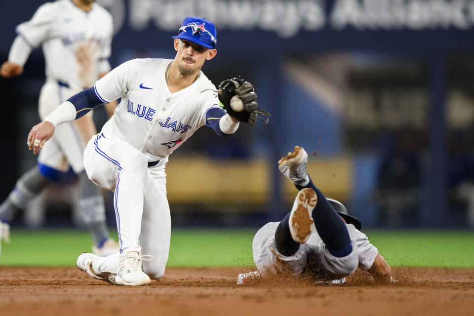 New York Yankees shortstop Anthony Volpe, right, steals second base as Toronto Blue Jays second baseman Cavan Biggio attempts the tag during a baseball game in Toronto on Monday, April 15, 2024. (Christopher Katsarov/The Canadian Press via AP)