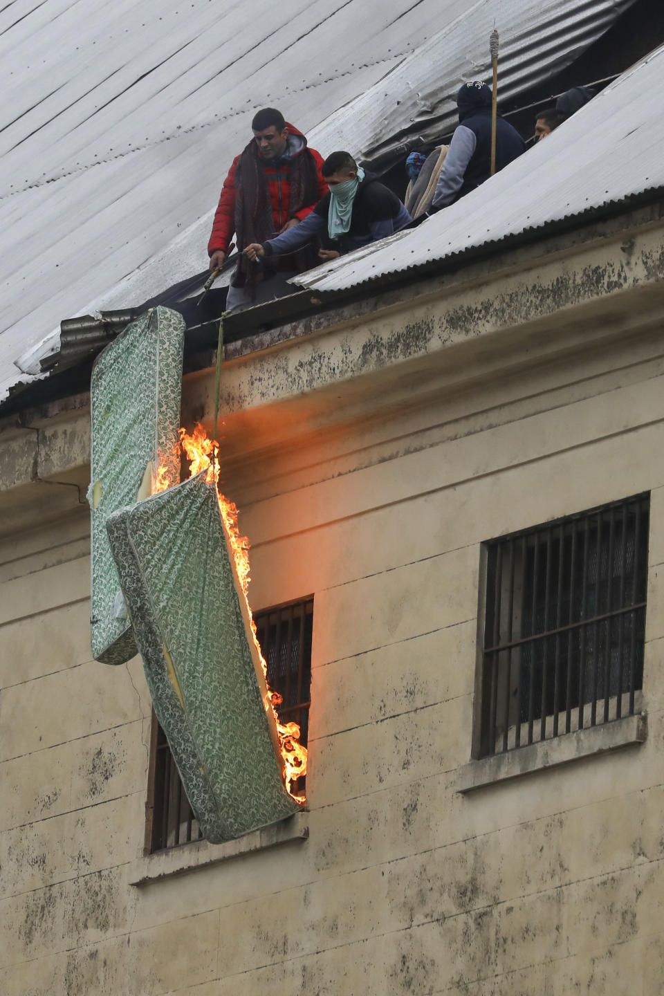 Rioting inmates burn mattresses from the roof of the Villa Devoto prison to protest against authorities who they say are not doing enough to prevent the spread of coronavirus inside the jail in Buenos Aires, Argentina, Friday, April 24, 2020. (AP Photo/Natacha Pisarenko)