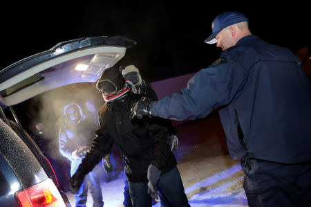 Refugees that walked along railway tracks from the United States to enter Canada are detained by the Royal Canadian Mounted Police at Emerson, Manitoba, Canada February 26, 2017. REUTERS/Lyle Stafford